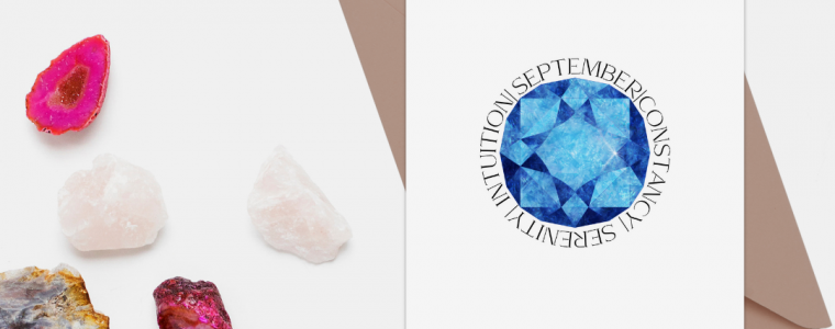 September birthstone card on a table next to a collection of crystals